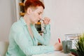 Young woman with short hair at desk writes thoughtfully in red pencil. Profile portrait of woman writer at work