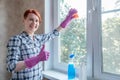 Young woman with short hair stands by window with hand thumb up. Cleaning service worker washes windows Royalty Free Stock Photo