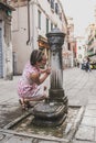 A young woman on the background of the city drinks water from a fountain Royalty Free Stock Photo