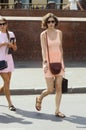 Young woman in a short pink dress summer, sunny day crossing the road near the restaurant Prague name Sunglasses