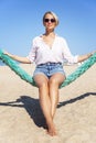 A young woman in shorts and a shirt is relaxing on a sandy beach on a sunny day. Relaxation, travel and freedom. Vertical Royalty Free Stock Photo