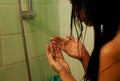 Young woman in the shower surprised she is losing hair, noticed split ends receding hairline. Gray background. Royalty Free Stock Photo