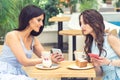 Young woman is showing on cell phone something to girlfriend at cafe Royalty Free Stock Photo