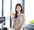 Young woman showing drinking glass with water in kitchen Royalty Free Stock Photo