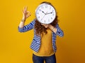 Young woman showing ok gesture holding clock in front of face Royalty Free Stock Photo