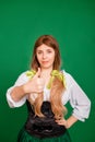Young woman showing thumb up gesture and smiling isolated on green background. St. Patrick`s Day and Oktoberfest Royalty Free Stock Photo