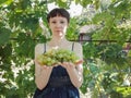 Young woman shows a heap of green grapes harvested by herself in a little grapeÃ¢â¬â¢s vineyard.