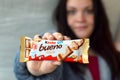 Young woman shows Kinder Bueno white Chocolate Candy Bar in colored wrapping. Kinder Bueno by Italian Confectionery Manufacturer Royalty Free Stock Photo