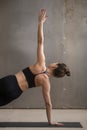 Young woman in Side Plank pose, grey studio background, closeup Royalty Free Stock Photo