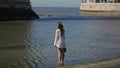 Young woman sightseeing, walking shoeless in water