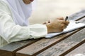 Young woman signing form, sitting on wooden table