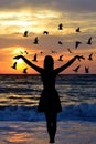 Young woman silhouette with birds on the seaside