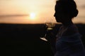 Young woman silhouette drinking wine on the hill at sunset. Royalty Free Stock Photo