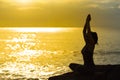 Young woman silhouette meditating and practicing yoga on the beach at sunset.Slim girl with yoga. Royalty Free Stock Photo