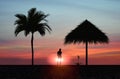 Young woman  silhTropical sunset  ,people silhouette on horizon, palm tree on pink gold orange sky  at beach on promenade relaxing Royalty Free Stock Photo