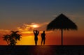 Young woman  silhTropical sunset  ,people silhouette on horizon, palm tree on pink gold orange sky  at beach on promenade relaxing Royalty Free Stock Photo