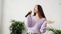 Young woman sing at home. Karaoke black microphone. House lyrics dance.