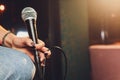 Young woman singing in karaoke and holding a microphone close-up. Singer at a party or concert on the background of a Royalty Free Stock Photo