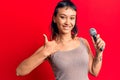 Young woman singing song using microphone smiling happy and positive, thumb up doing excellent and approval sign Royalty Free Stock Photo