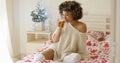 Young woman sipping tea while seated in bed Royalty Free Stock Photo