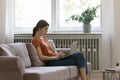 Young woman sit on couch at home working on laptop Royalty Free Stock Photo