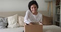 Young woman sit on couch opens parcel box feels satisfied