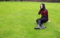 Young woman sit on grass and listening to music with headphones Royalty Free Stock Photo