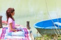 Young woman sit in a meditative yoga position on wooden pontoon on the lake hold magnolia flower