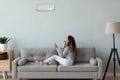 Young woman turn on air conditioner in living room