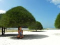 Young woman sit on the sand on a tropical sandy beach in the shade of trees. Malibu Beach, Koh Phangan, Thailand Royalty Free Stock Photo