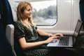 Young woman sit in train alone. Work and travel at same time. Vacation time or holidays period. Typing on laptop Royalty Free Stock Photo