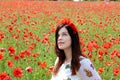 Young woman sitiing in poppies looking up