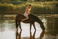 Woman sits astride a horse that drinks water