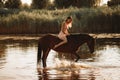 Woman sits astride a horse that produces splashes on water