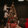 Young woman sits on back shoulders of man and decorates a Christmas tree Royalty Free Stock Photo