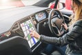 Woman sits behind wheel in car and uses electronic dashboard. Girl traveler looking for way through navigation system.