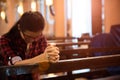 Young woman sits on a bench in the church and prays to God. Hands folded in prayer concept for faith Royalty Free Stock Photo