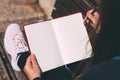 Young woman sits on bench in park with blank notebook and pen on her hands. Royalty Free Stock Photo