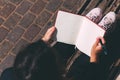 Young woman sits on bench in park with blank notebook and pen on her hands.