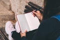 Young woman sits on bench in park with blank notebook and pen on her hands. Royalty Free Stock Photo