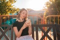 A young woman sits on a bench in a Park and uses a smartphone. Summer. The concept of social dependency and modern technologies