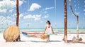 Young woman sits on a big swing alone in a tropical paradise during holidays, holding sun hat in her hand Royalty Free Stock Photo