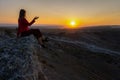 A young woman sits on the edge of a cliff and looks at the sun Royalty Free Stock Photo