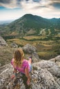 Young woman sits on the edge of the rocky cliff