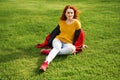 Young woman sits on green grass in spring park Royalty Free Stock Photo