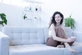 young woman sits on her sofa with a mug in her hand smiles and looks away in modern home Royalty Free Stock Photo