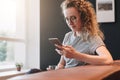 Young woman sits on leather sofa,uses smartphone,working.Hipster girl ichatting,blogging,checking email Royalty Free Stock Photo