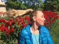 The young woman sits near the bright blossoming tulips