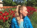 The young woman sits near the bright blossoming tulips