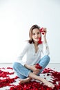 young woman sits among the red rose flower petals Royalty Free Stock Photo